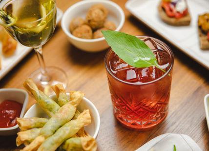 An image of a table with food and drinks, Signature Cocktails and Italian Bar Snacks. Sette