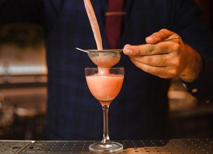 An image of a person making a drink, Signature Cocktails and Italian Bar Snacks. Sette