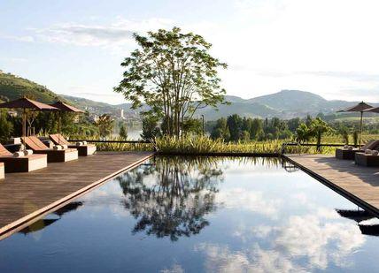 An image of a pool with lounge chairs and umbrellas, Three day break with spa treatment and dinner. Six Senses Douro Valley