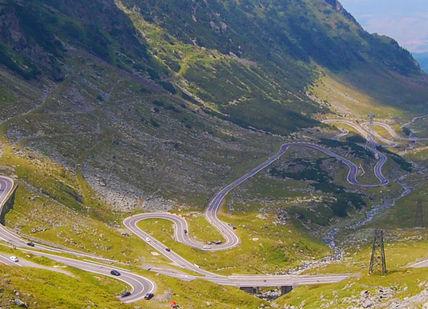 An image of a mountain road with a car driving down it, BMW 3 Series Rental for 4 days. SIXT Car Hire