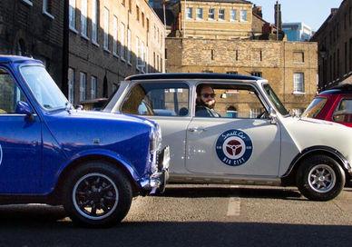 An image of two small cars parked in a street, Iconic London Tour in a Classic Mini Cooper. smallcarBIGCITY