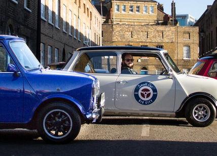 An image of two small cars parked in a street, Iconic London Tour in a Classic Mini Cooper. smallcarBIGCITY