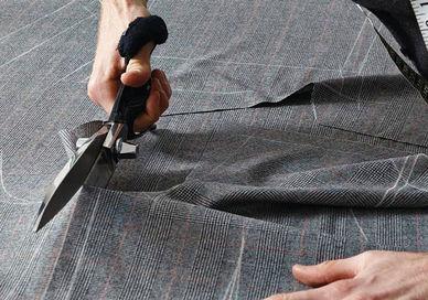 An image of a man cutting a piece of fabric, Create a Bespoke Two-Piece Suit. Stowers London