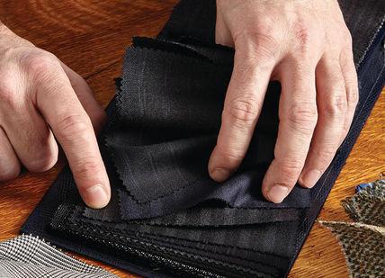 An image of a man's hands removing a piece of fabric, Create a Fully Bespoke Groom or Groomsman Suit. Stowers London
