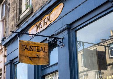 An image of a restaurant sign hanging on the side of a building, Edinburgh, Scotland. Taisteal