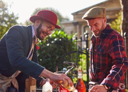 An image of two men making drinks, Bike Ride and Gin Tour. Tally Ho