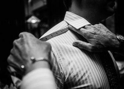 An image of a man adjusting his tie, Create Bespoke Shirts. Turnbull & Asser - London