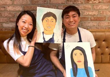 An image of a man and woman holding up a picture of a man and woman, Fun Paint Your Partner Class. Undergrounder