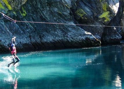 An image of a person jumping off a rope into a river, Return Transfer from Ålesund Airport to Hotel Juvet. Valldal Naturopplevingar