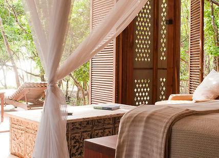 An image of a bedroom with a bed and a couch, Kitala suite on Vamizi Island. Vamizi Island