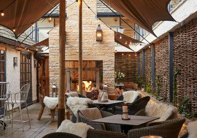 A patio with tables and chairs and a fireplace.