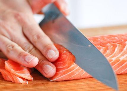 An image of a person cutting a piece of salmon, Private Sushi Class. Yuki Gomi