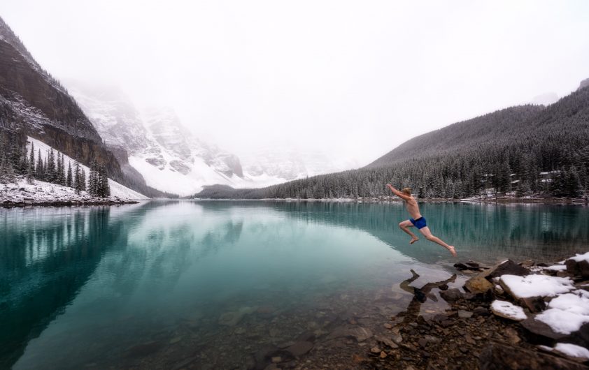 Man jumping into cold lake in winter
