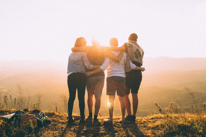 Happy group of friends looking over a sunset