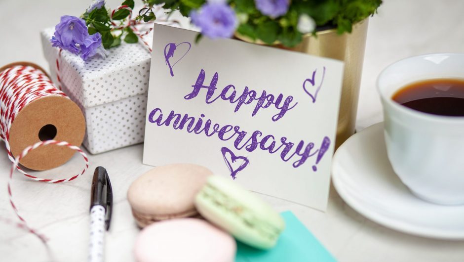 Writing a Happy Anniversary postcard on white marble table
