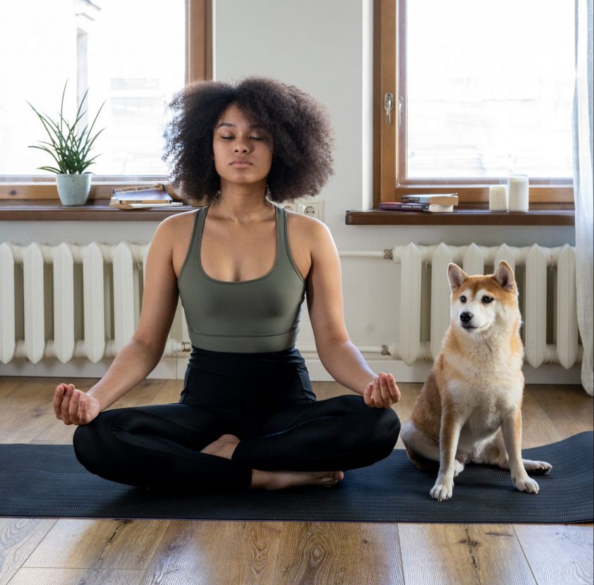 Woman practicing healthy habit of meditating with her dog