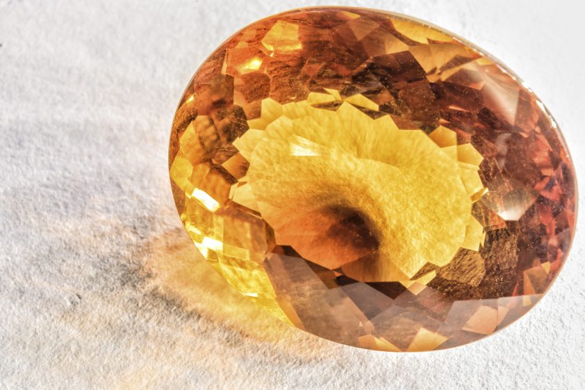 Beautiful citrine quartz crystal faceted on white surface