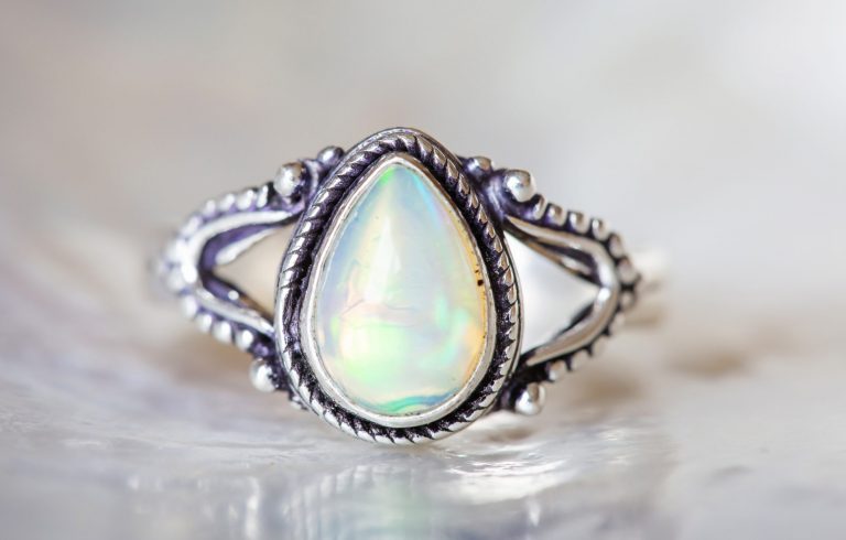 Silver ring with white opal gemstone on pearl background