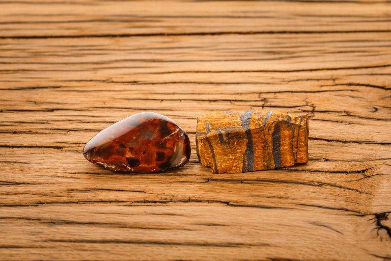 Piece of pietersite and rough tiger eye originating from Namibia Africa on wood. Pietersite metamorphic gem stone type of tiger eye.
