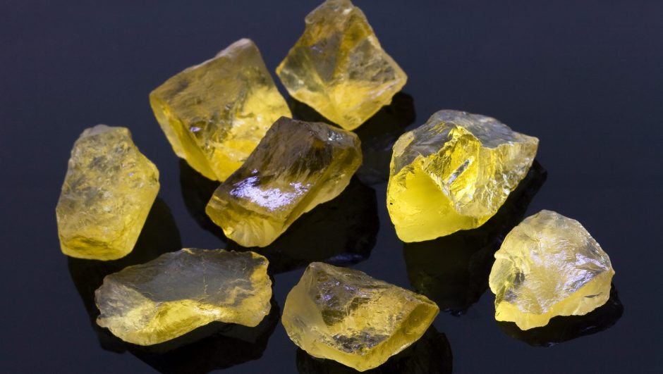 Rough lemon quartz gem stones on a black surface