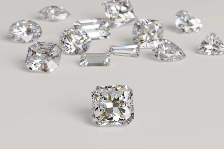 Variously cut diamonds scattered on white background with a radi