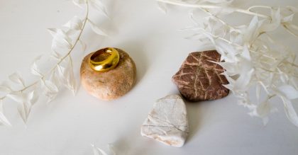 Jewellery, white branch and ocean pebble on a white table