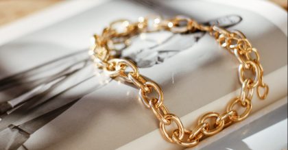 yellow gold chain bracelet on top of a magazine