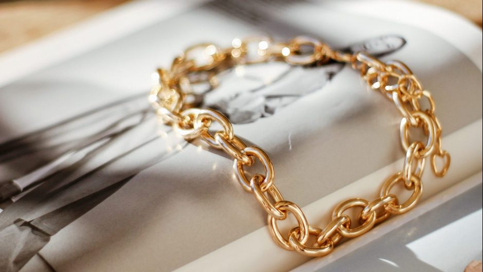 yellow gold chain bracelet on top of a magazine