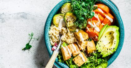 Buddha bowl with quinoa, tofu, avocado, sweet potato, brussels sprouts and tahini, copy space. Healthy vegan food concept.