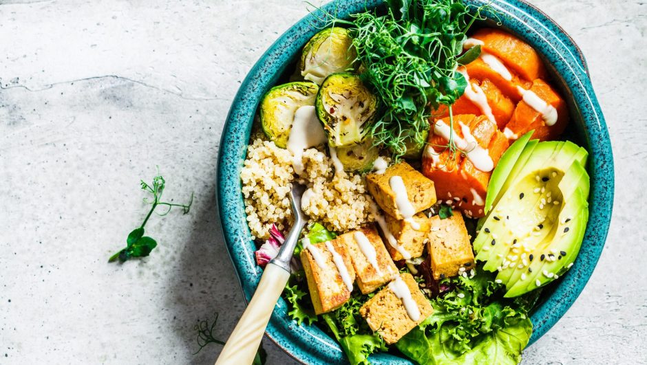 Buddha bowl with quinoa, tofu, avocado, sweet potato, brussels sprouts and tahini, copy space. Healthy vegan food concept.