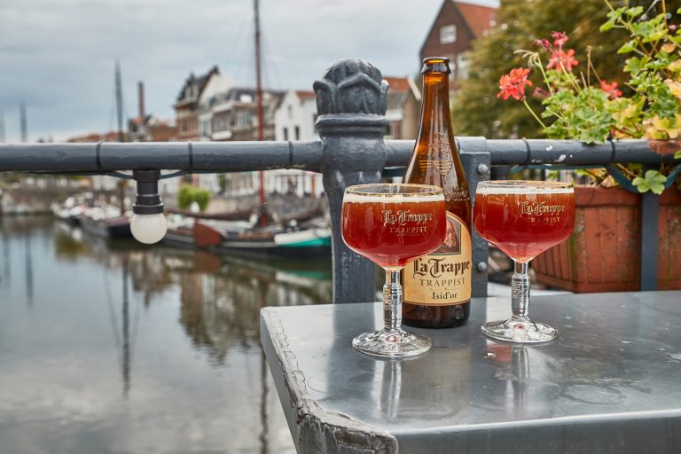 ROTTERDAM, THE NETHERLANDS - SEPTEMBER 22, 2019: La Trappe Dutch Trappist abbey beer poured into glasses on an outdoor terrace in Delfshaven, pleasant view over the canals, Cafe de Oude Sluis terrace