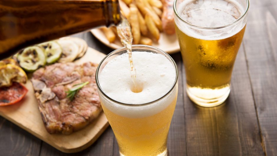 French Beer being poured into glass with gourmet steak and french fries