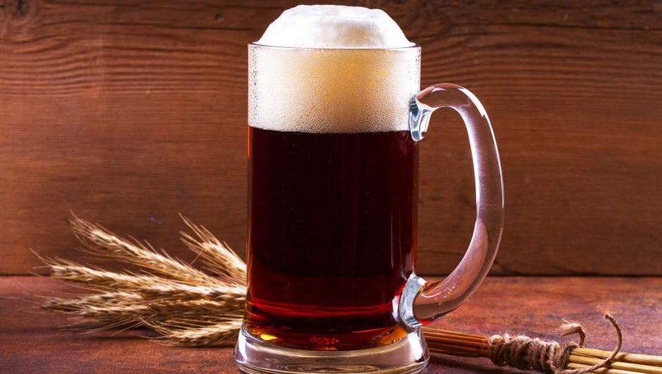 Glass of Scottish ale and barley cereal grain on rusty background