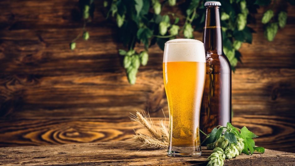 Glass of beer and bottle on old wooden table and wooden background