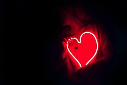 Woman holding a glowing heart in the dark